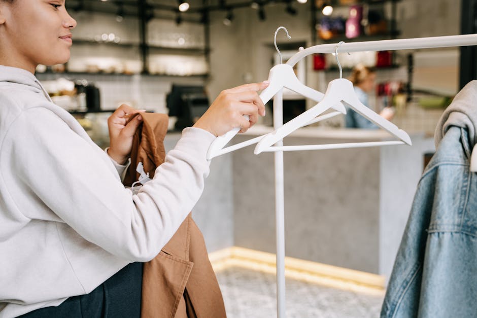 A woman browsing and selecting clothes in a modern boutique store with minimalistic interior.