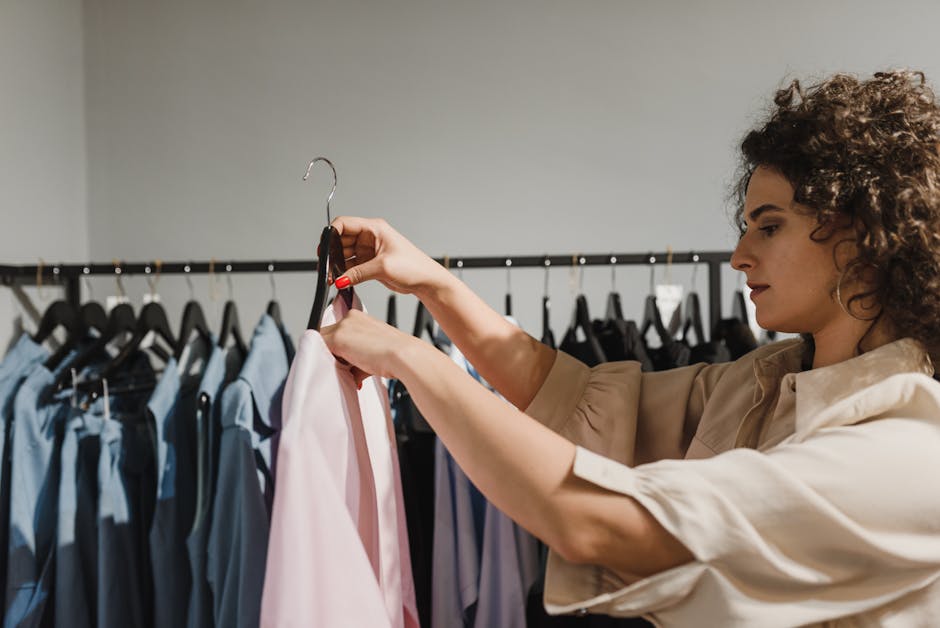 Side view of a woman browsing clothes on a rack in a boutique store.