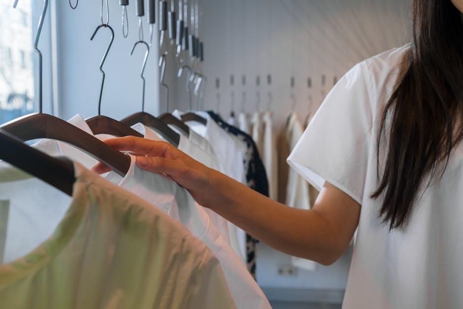 Close-up of a woman browsing clothes in a boutique, focusing on hangers.